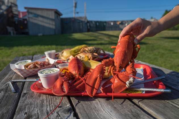 A tasty traditional New England meal of Atlantic lobster with Jonas crab and coleslaw and corn on the cob sits on a picnic table in Maine. Copyright: xLoopxImages TysonxPaulx TPL01024WT097