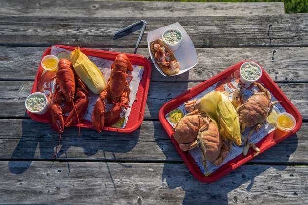 A tasty traditional New England meal of Atlantic lobster with Jonas crab and coleslaw and corn on the cob sits on a picnic table in Maine. Copyright: xLoopxImages TysonxPaulx TPL01024WT098