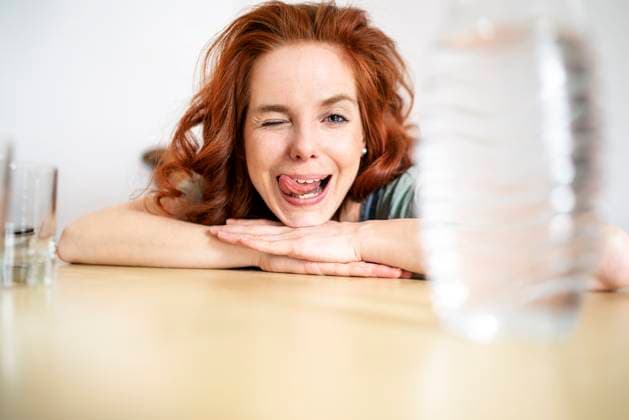 Creative Highlights Symbolfotos Portrait of cheerful woman winking and sticking out tongue while leaning on table at home model released, Symbolfoto property released, DMOF00156