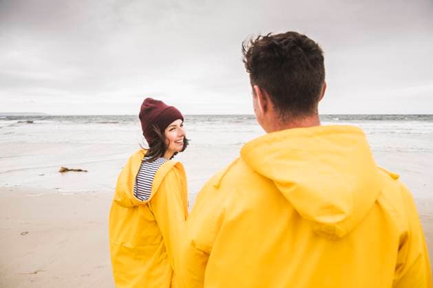 Creative Highlights Symbolfotos Young woman wearing yellow rain jackets and walking along the beach, Bretagne, France model released, Symbolfoto, UUF19689