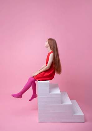 Creative Highlights Symbolfotos Teenage girl with red hair sitting on stairs in a studio with a pink background model released, Symbolfoto, VRAF01127