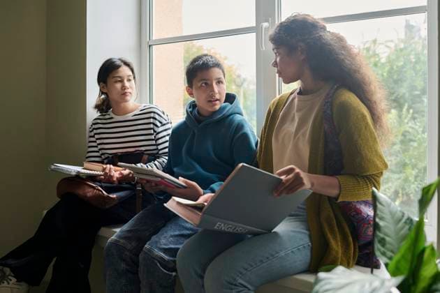 Three students talking in a school hall holding notebooks model released, Symbolfoto property released, DSHF02191