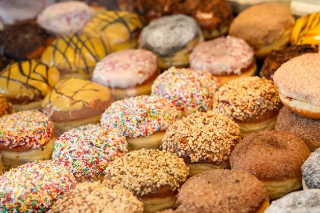 Bunt verzierte Berliner (Krapfen) zur Faschingszeit in den Auslagen der Bäckerei In der Bäckerei sind bunt verzierte Berliner ausgestellt. Gebäck aus süßem Hefeteig für die Karnevalszeit Copyright: xZoonar.com SandraAlkadox 23008528