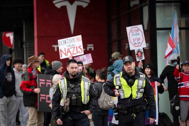March 29, 2025, Vancouver, B.C, CANADA: Members of the Vancouver Police cross the street as people gather outside a Tesla dealership to protest, in Vancouver, B.C., on Saturday, March 29, 2025. Vancouver CANADA  - ZUMAc35_ 20250329_zaf_c35_058 Copyright: xTijanaxMartinx