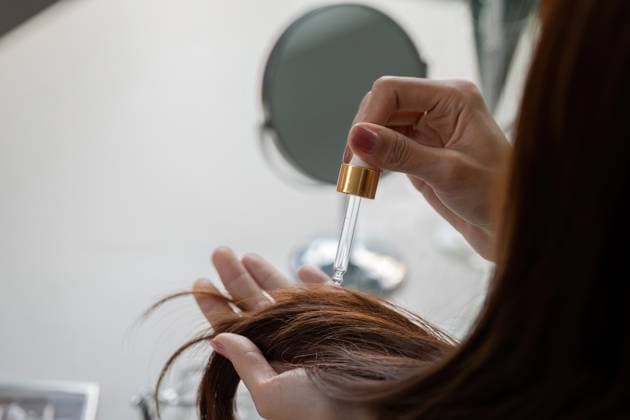 Haarpflege und Schönheitsroutine. Haarserum für gesunde und strahlende Locken auftragen. A close-up of a person applying hair serum with a dropper, focusing on hair health and shine, emphasizing a self-care beauty routine. ,model released, Symbolfoto Copyright: xZoonar.com NATEExMEEPIANx 23119499 ,model released, Symbolfoto ,property released