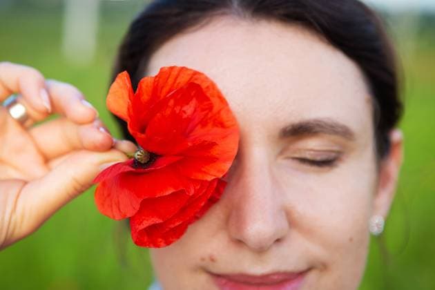 Creative Highlights Symbolfotos Eine junge Frau hält sanft eine leuchtend rote Mohnblume an ihr geschlossenes Auge und schafft damit einen ruhigen und schönen Moment im Freien A young woman gently holds a vibrant red poppy flower to her closed eye, creating a serene and beautiful moment outdoors. ,model released, Symbolfoto Copyright: xZoonar.com SergiyxArtsabax 23126994 ,model released, Symbolfoto ,property released
