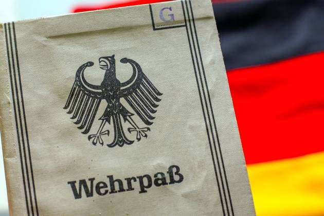 Ein Wehrpaß aus den 1950er Jahren liegt auf einer Deutschland-Fahne Symbolbild Wehrpflicht *** A military service pass from the 1950s lies on a German flag Symbolic image of compulsory military service