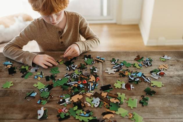 Creative Highlights Symbolfotos Boy 8-10 looking down putting together puzzle on table at home Grimes, Iowa, United States R_LIPF250401-1694467-01 EDITORIAL USE ONLY