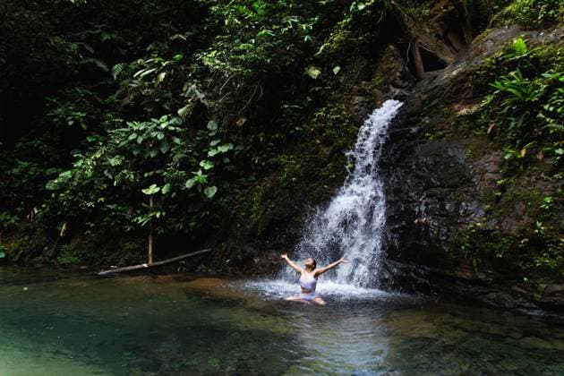 Young woman enjoying and stretching arms in a natural pool under a waterfall in the Choco Andino rainforest, Ecuador. This image captures the spirit of ecotourism and adventure in a biodiverse tropical landscape. Model Released Cardellach_ID27637_793647_017 Copyright: xCardellachx RECORD DATE NOT STATED