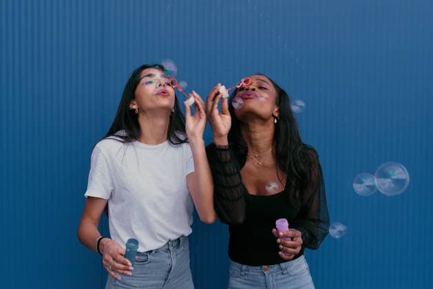 Creative Highlights Symbolfotos Two young friends joyfully blowing bubbles against a vibrant blue background, capturing the essence of carefree fun and friendship. The scene is lively and colorful. Model Released Jultud_ID27592_792233_001 Copyright: xJultudx RECORD DATE NOT STATED