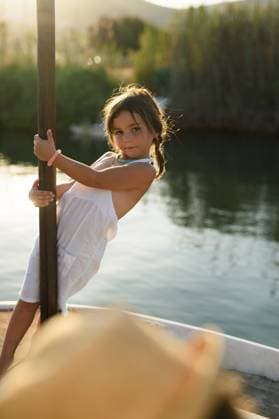 Creative Highlights Symbolfotos A young girl, dressed in a light summer outfit, playfully stands on a boat in the serene waters of Andratx, Mallorca, part of the picturesque Balearic Islands in Spain. Model Released MagdalenaCarli_ID27192_782033_003 Copyright: xMagdalenaxCarlix