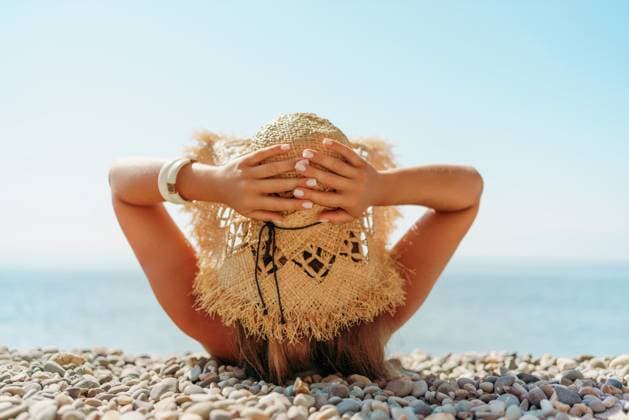 Beach Relaxation woman lies on a pebble beach, legs raised, and arms spread out. The concept of travel, vacation at sea., model released, , property released, , 57811536.jpg, beach, relaxation, sunshine, pebbles, water, clear skies, calmness, tranquility, nature, outdoors, serene, straw hat, shadows, highlights, relaxed, tranquil, waterside, sunlight, peaceful, mood, blue-green sea, individual, face down, legs raised, arms spread out. RECORD DATE NOT STATED