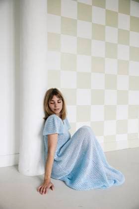 Creative Highlights Symbolfotos Woman in blue crochet dress with soft focus against a checkered wall Amsterdam, North Holland, Netherlands CR_RTBZ25040582-1699923-01 ,model released, Symbolfoto