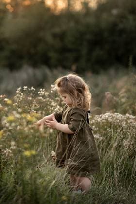 Creative Highlights Symbolfotos A girl standing in the tall grass and looking down, pointing finger. Corby, England, United Kingdom R_JNDO250404B-1696023-01 ,model released, Symbolfoto