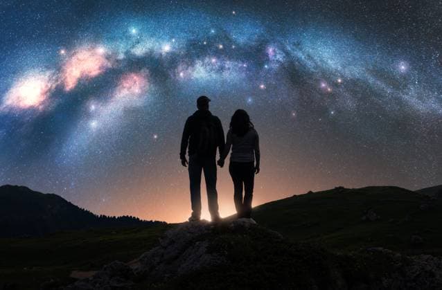 ï¿½ouple of hikers holding hands standing on a rocky outcrop in mountains, under night starry sky with glowing Milky Way. Colorful landscape with silhouettes of man and woman, bright stars and milky way Model Released DenisBilytskyi_ID27418_786785_014 Copyright: xx