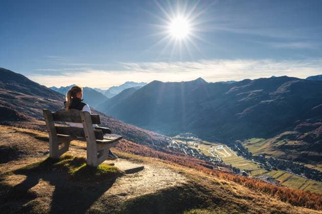 Young woman hiker sitting on the bench on grassy mountain peak enjoying stunning view of valley with high mountain peaks during golden hour sunset in autumn. Hiking in Italy, Livigno. Girl in Alps Model Released DenisBilytskyi_ID27833_798984_008 Copyright: xx