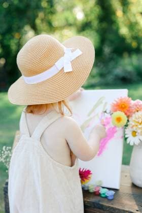 Creative Highlights Symbolfotos Child painting outdoors in a sun hat, surrounded by flowers. Pittsburgh, Pennsylvania, United States CR_QIWH25010877-1624128-01 ,model released, Symbolfoto