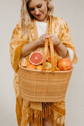 Creative Highlights Symbolfotos Woman in yellow robe holding basket of assorted citrus fruits. Los Angeles, California, United States R_AUAU250409-1275353-01