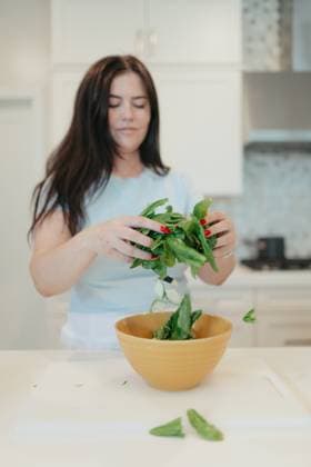 Woman adding fresh spinach leaves into a yellow bowl. Vista, California, United States R_AUAU250409B-1700350-01 ,model released, Symbolfoto ,property released