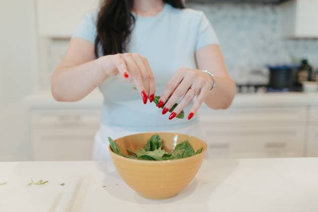 Woman tearing fresh spinach into a yellow bowl. Vista, California, United States R_AUAU250409B-1700366-01