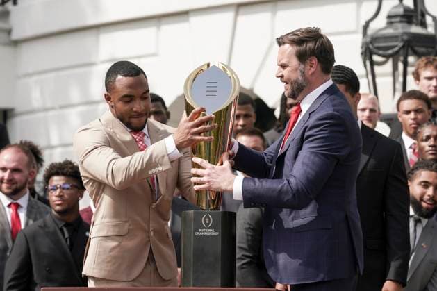 Ohio State University football player TreVeyon Henderson, left, helps replace the top of the trophy after Vice President JD Vance dropped the base during a welcoming ceremony by President Trump for the 2025 College Football National Champions - The Ohio State University on the South Lawn of the White House in Washington, DC on Monday, April 14, 2025.  WAS20250414588 KenxCedeno