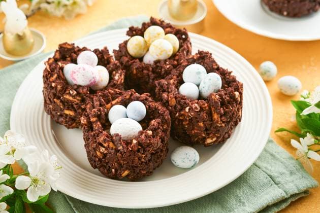 Ostern Schokolade Nest Kuchen mit Mini-Schokolade Süßigkeiten Eier mit blühenden Kirsche oder Apfel Blumen auf gelben Hintergrund Tisch. Kreatives Rezept für Ostertisch mit Feiertagsdekorationen. Ansicht von oben. Easter chocolate nest cake with mini chocolate candy eggs with blossoming cherry or apple flowers on yellow background table. Creative recipe for Easter table with holiday decorations. Top view. (License=RF) Copyright: xZoonar.com KatsiarynaxHuravax 23185404