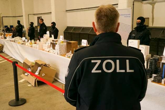News Themen der Woche KW16 News Bilder des Tages Beamter mit der Aufschrift Zoll auf seiner Jacke bewacht Viagra, Testosteron, Aufputschmittel Medikamente Verpackungen Gold und Geld liegen auf einem Tisch waehrend der Zoll Praesentation von sichergestellten Dopingmitteln, Drogen und Vermoegenswerten wie Bargeld und Gold in einer Halle auf dem Gelaende des Zollfahndungsamtes Hamburg17.04.2025 Der Hamburger Zoll hat einen illegalen Dopingmittel und Drogenvertrieb zerschlagen Die Beamten hatten einen Haendlerring von 3 Bruedern festgenommen die Sachen sichergestellt.Dabei wurden Vermögenswerte in Höhe von 189.000 Euro in Bar sowie Gold im Wert von 50.000 Euro Hamburg Deutschland *** Officer with the inscription customs on his jacket guards Viagra, testosterone, stimulant drugs packaging go