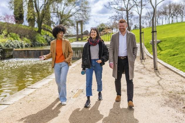 Drei junge Berufstätige genießen einen Spaziergang und unterhalten sich während ihrer Mittagspause in einem sonnigen Stadtpark Three young professionals enjoy a walk and talk together during their lunch break in a sunny city park Copyright: imageBROKER UnaixHuizi ibluhu13098662.jpg ,model released, Symbolfoto ,property released