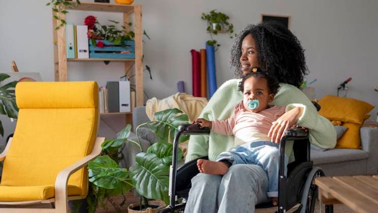 Cute girl sitting on mother with disability in wheelchair at home model released, Symbolfoto property released, JCCMF11740