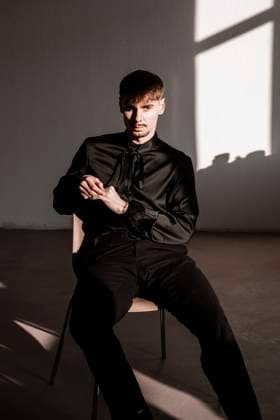 Creative Highlights Symbolfotos Young man in a black shirt sitting indoors with a serious expression model released, Symbolfoto, NGF00887
