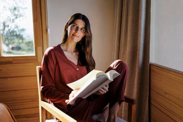 Woman relaxing and reading a book in a cozy cabin model released, Symbolfoto property released, EBIF00050