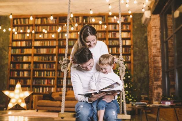 Familie mit Baby entspannen Zu Hause Swing Seat im gemütlichen dunklen Wohnzimmer an Weihnachten eve. Familie hat Spaß auf der Seesäge. Winterabend mit Familie und Kind. Familienlesebuch im Wohnzimmer Family with baby relaxing at home swing seat in cosy dark living room on Christmas eve. Family having fun on the sea saw. Winter evening with family and child. Family reading book in living room Copyright: imageBROKER fotoliza.ua ibxiqx13301043.jpg ,model released, Symbolfoto ,property released