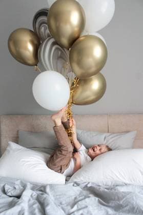 Creative Highlights Symbolfotos A blonde boy is playing with balloons on the bed. Barnaul, Altai Krai, Russia R_DQXQJK210428-732121-01 ,model released, Symbolfoto