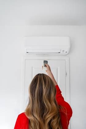 IMAGO Creative, Jahreszeit Sommer, Hitze Frau mit Fernbedienung, die auf die Klimaanlage gerichtet ist. Woman holding remote control aimed at the air conditioner. (License=RF) ,model released, Symbolfoto Copyright: xZoonar.com DmitrixMarutax 23343688 ,model released, Symbolfoto ,property released