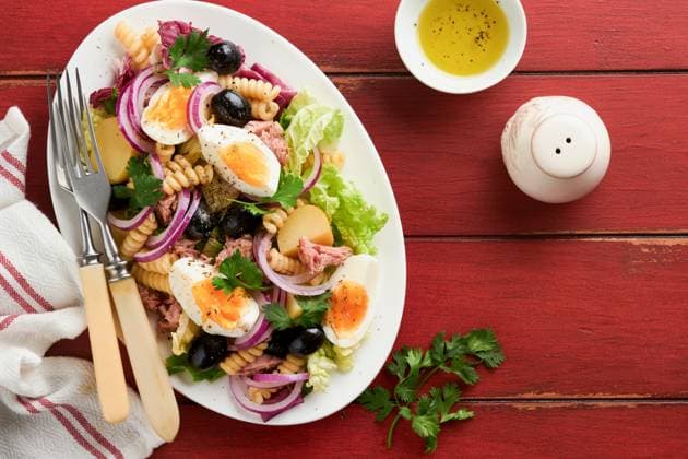 Thunfischsalat mit Nudeln, Eiern, Kartoffeln, Oliven, roten Zwiebeln und Sauce in weißem Teller auf altem roten rustikalen Tisch Hintergrund. Nicoise Salat. Französische Küche. Ansicht von oben. Flach gelegt. Tuna salad with pasta, eggs, potatoes, olives, red onions and sauce in white plate on old red rustic table background. Nicoise salad. French cuisine. Top view. Flat lay. (License=RF) Copyright: xZoonar.com KatsiarynaxHuravax 23357831
