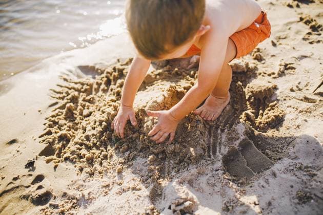 Ein kleiner Junge baut bei Sonnenuntergang am Ufer des Teiches Figuren aus dem Sand, die Hände graben den Sand in einem knackigen Plan um A little boy builds figures from the sand on the shore of the pond at sunset of the day, hands dig up the sand in a crisp plan Copyright: imageBROKER fotoliza.ua ibxiqx13296635.jpg ,model released, Symbolfoto ,property released