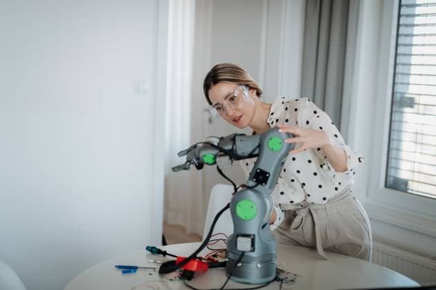 Female engineer building and programming a robotic arm at home. Female engineer building and programming a robotic arm at home. Robotics concept. model released