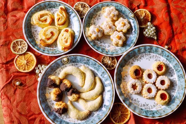 verschiedene Weihnachtsplätzchen, angerichtet auf einzelnen Tellern auf roter Weihnachtstischdecke *** Miscellaneous Christmas cookies, served at individual Plates at Red Christmas tablecloth