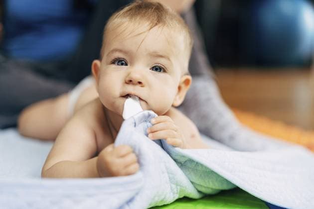 Creative Highlight Symbolbilder Ein kleines Baby in Windeln liegt mit dem Bauch auf einer blauen Decke und hält den Rand mit seinen Händen und Zähnen fest Tiny baby in diapers lies with his tummy on a blue blanket and holds the edge with his hands and teeth. Copyright: imageBROKER NadtochiyxVladimir ibxiqx13174174.jpg ,model released, Symbolfoto ,property released