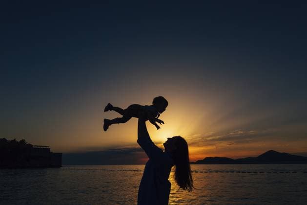 Creative Highlight Symbolbilder Die Mutter wirft ihren kleinen Sohn hoch und spielt mit ihm am Strand bei Sonnenuntergang Mom throws up her little son and plays with him on the beach at sunset . Copyright: imageBROKER NadtochiyxVladimir ibxiqx13172755.jpg ,model released, Symbolfoto ,property released