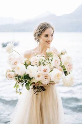 Eine lächelnde Braut mit einem Blumenstrauß steht am Ufer des Comer Sees vor der Kulisse der Berge Smiling bride with a bouquet of flowers stands on the shore of Lake Como against the backdrop of mountains. Copyright: imageBROKER NadtochiyxVladimir ibxiqx13172161.jpg ,model released, Symbolfoto ,property released