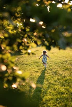 IMAGO Creative, Ostern, Bräuche, Osterspaziergang #2 child running through field in park. view fromframe of branches Corby, England, United Kingdom R_JNDO25050500-1707728-01 ,model released, Symbolfoto