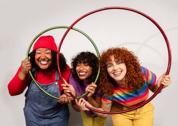 MR_ID29105_21276_KellyCundumi.jpg, MR_ID29105_21274_AlejandraTorres.jpg, MR_ID29105_21275_JudithPedrosa.jpg Three women share joyful moments, smiling brightly as they play together with colorful hula hoops. Their cheerful expressions and vibrant outfits create a lively scene. Model Released VictorTorres_ID29105_888855_065 Copyright: xVictorxTorresx