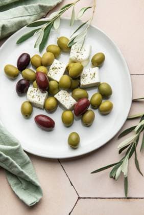 Weißer Teller mit grünen und schwarzen Oliven, Fetakäsewürfeln und Olivenzweigen Delicious greek salad with green and black olives, and feta cheese cubes seasoned with oregano, served on a white plate, accompanied by olive branches (License=RF) Copyright: xZoonar.com OlenaxRudox 23386893