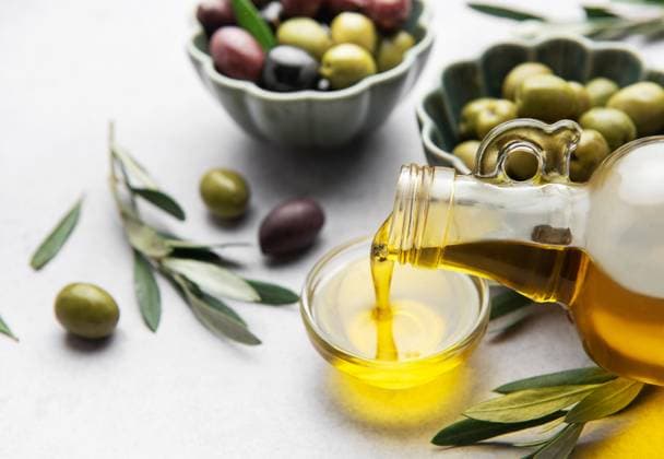 Natives Olivenöl in eine kleine Schale mit Oliven und Olivenzweigen gießen Golden olive oil pouring from a glass bottle into a small bowl, surrounded by fresh olives and olive branches (License=RF) Copyright: xZoonar.com OlenaxRudox 23386968
