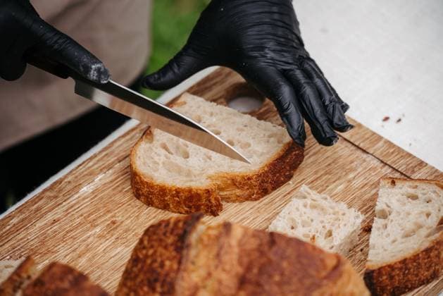 Cook cutting rustic sourdough bread on cutting board. Cook cutting resh rustic sourdough bread on wooden cutting board. model released