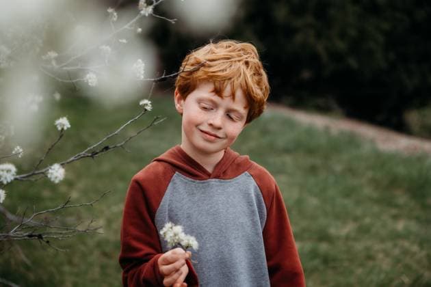 Creative Highlight Symbolbilder Redheaded boy smiling in spring garden while holding white blossoms Grimes, Iowa, United States CR_LIPF250508B-1722628-01 ,model released, Symbolfoto