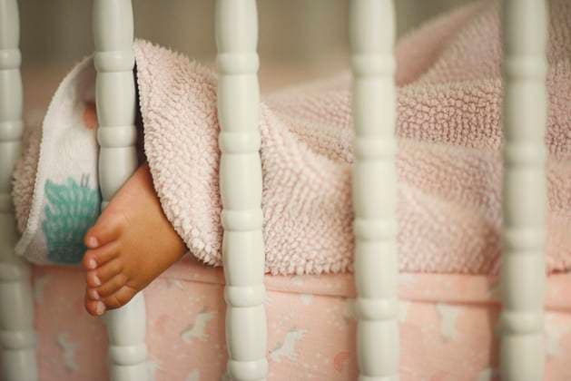 Brown sleeping babies with foot out in vintage crib. United States, Florida, Floral City R_YWQX250507-1400160-01 ,model released, Symbolfoto