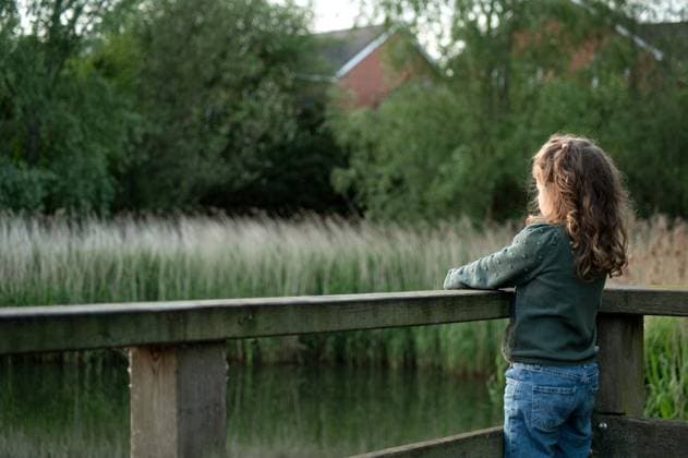 IMAGO Creative, Ostern, Bräuche, Osterspaziergang #2 Back of girl stand in wooden bridge and looking at the pond Corby, England, United Kingdom R_JNDO250511B-1724952-01 ,model released, Symbolfoto