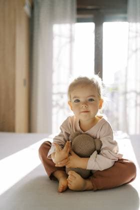 Creative Highlight Symbolbilder Kleines Mädchen, das auf dem Bett sitzend einen Teddybären umarmt Little girl hugging a teddy bear while sitting on the bed. Copyright: imageBROKER NadtochiyxVladimir ibxiqx13181772.jpg ,model released, Symbolfoto ,property released